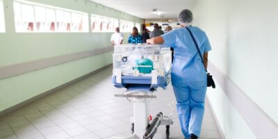 Health worker - person walking on hallway in blue scrub suit near incubator
